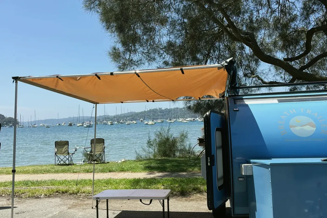 A light-blue Breath with its awning out by a Sydney bay (awning optional)