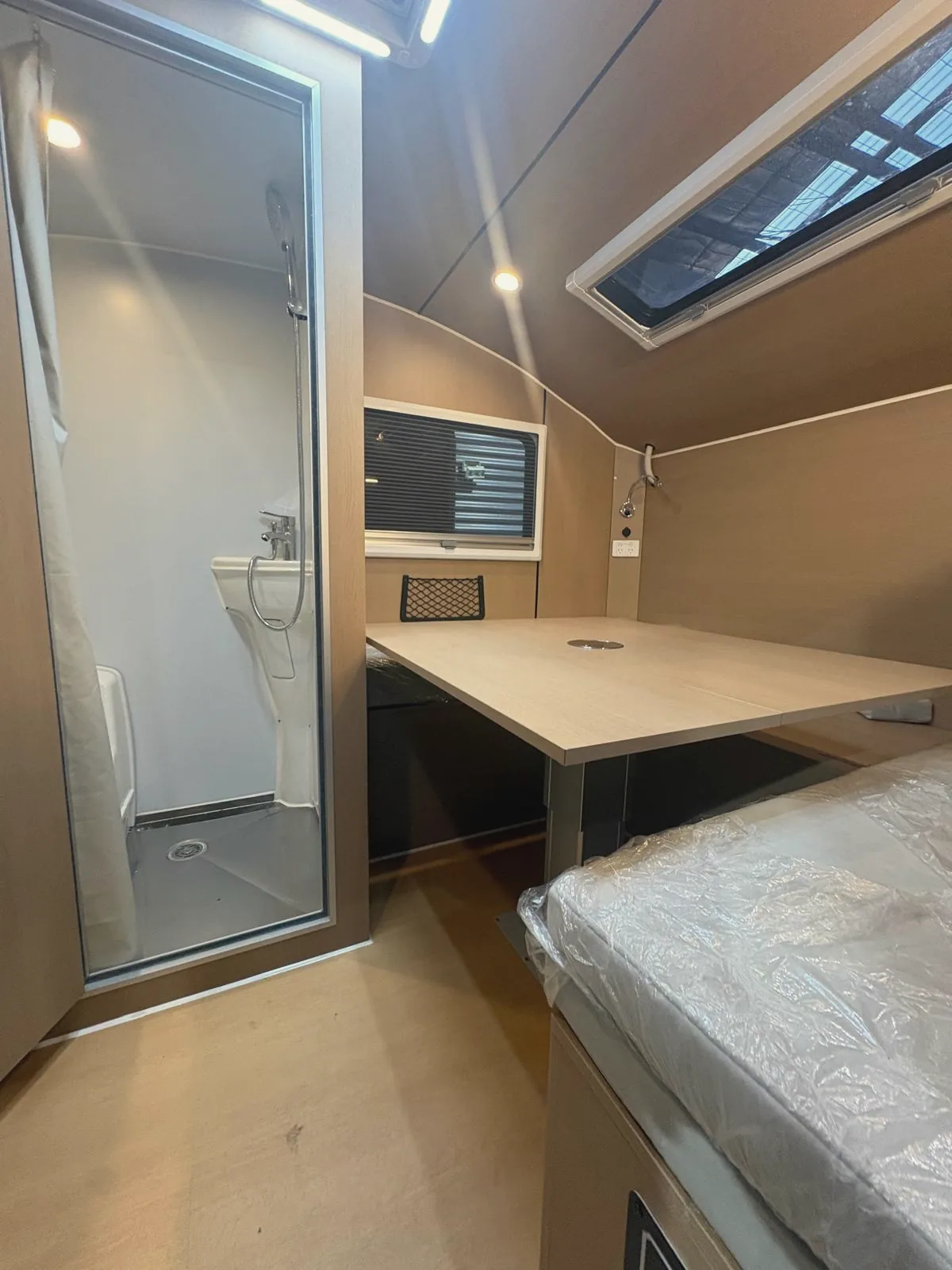 The dinette table beside the bed, shower cubicle on the left