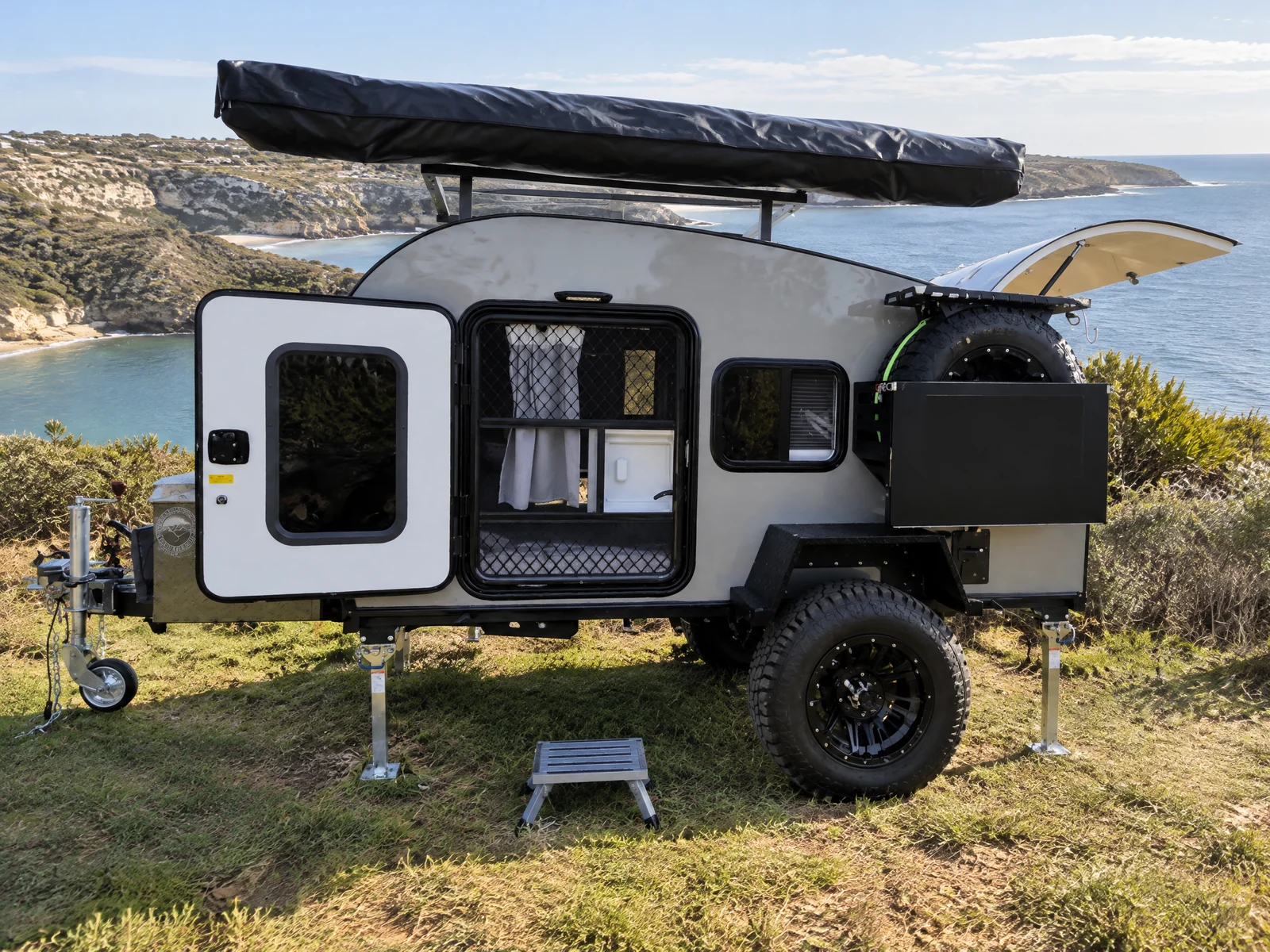 Breath Ultra at a coastal campsite above a sheltered bay with rear kitchen open and limestone cliffs behind