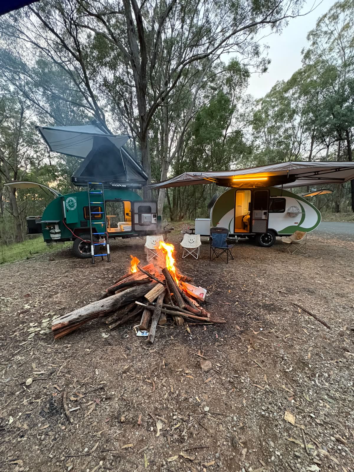 Two Breath Trailers parked beside a campfire at dusk