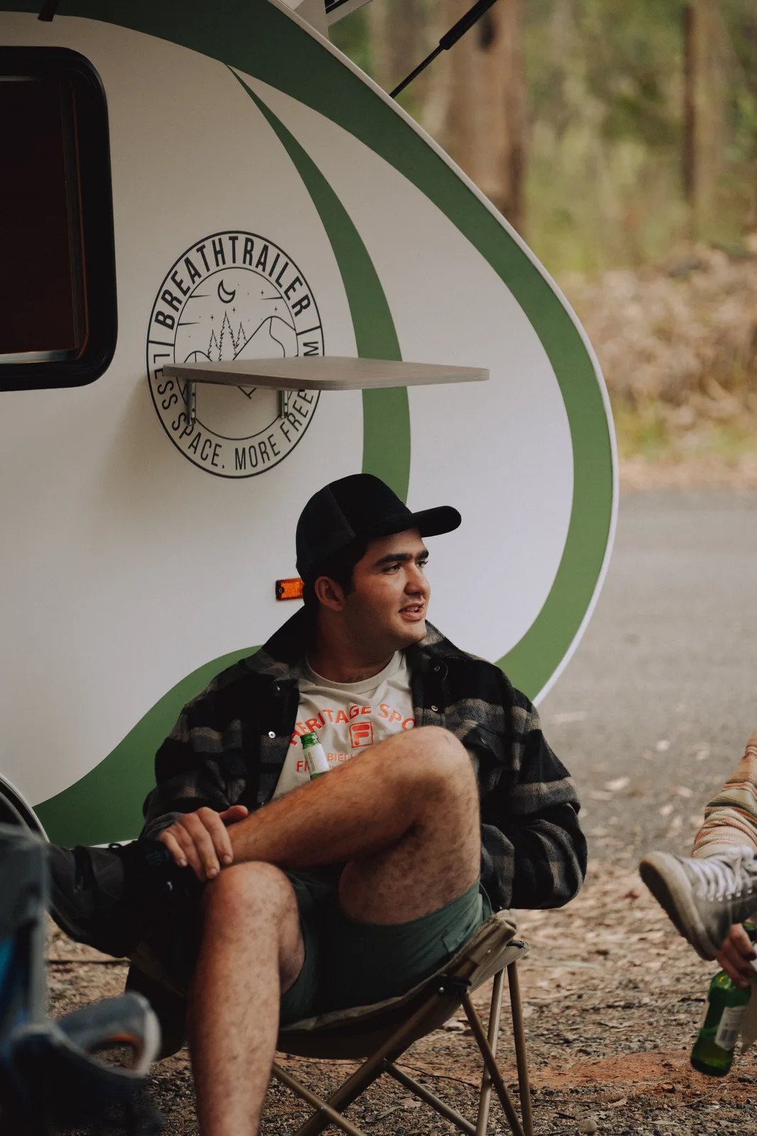 Breath Plus owner relaxing in camp chair by trailer