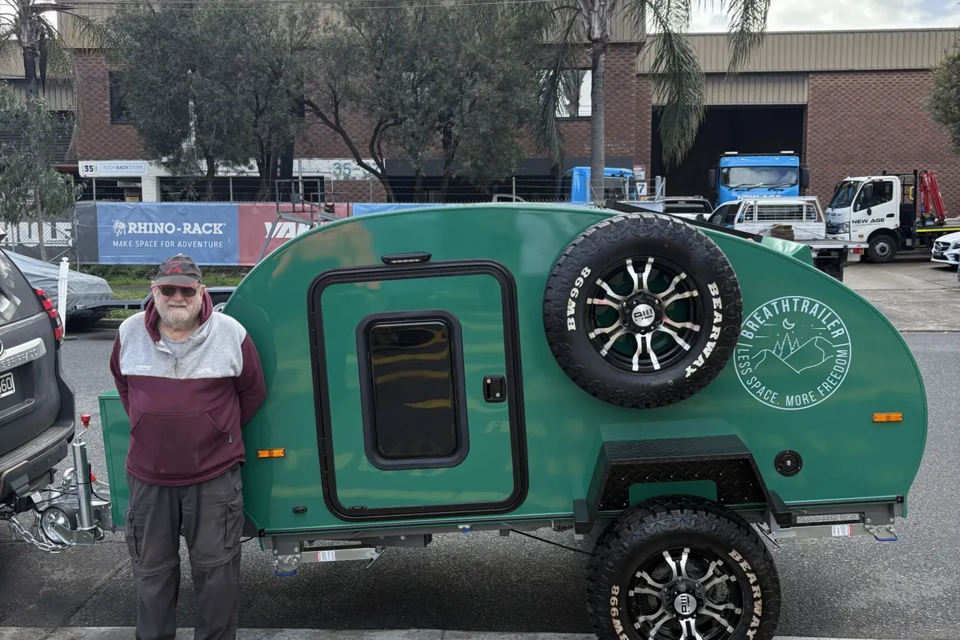 Breath Trailer owner beside his green teardrop camper