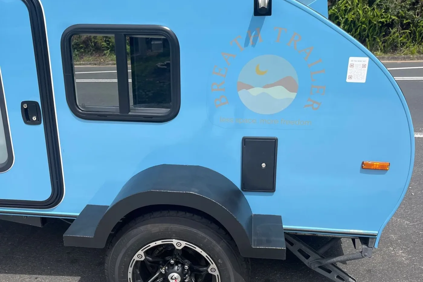 Sky blue compact Breath teardrop side panel with pastel Breath Trailer logo and sliding window