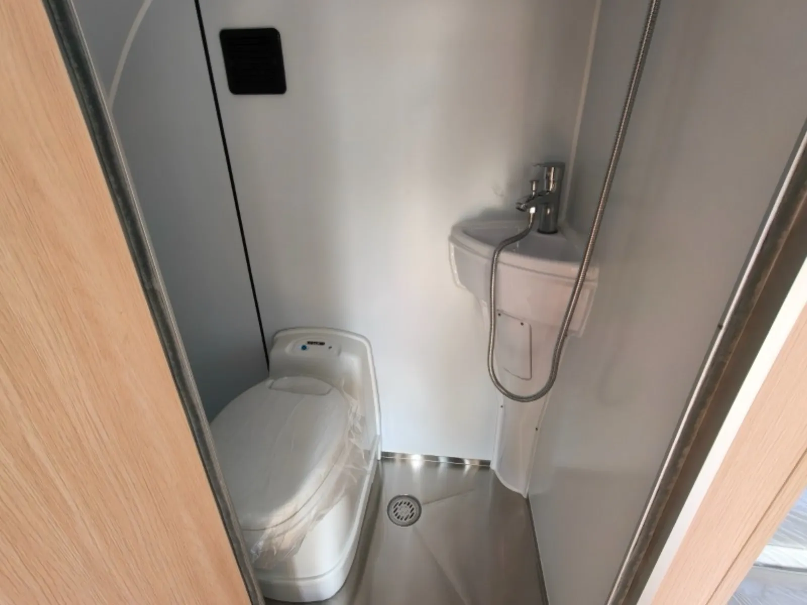 Breath Max bathroom with cassette toilet, corner basin, handheld shower hose and floor drain