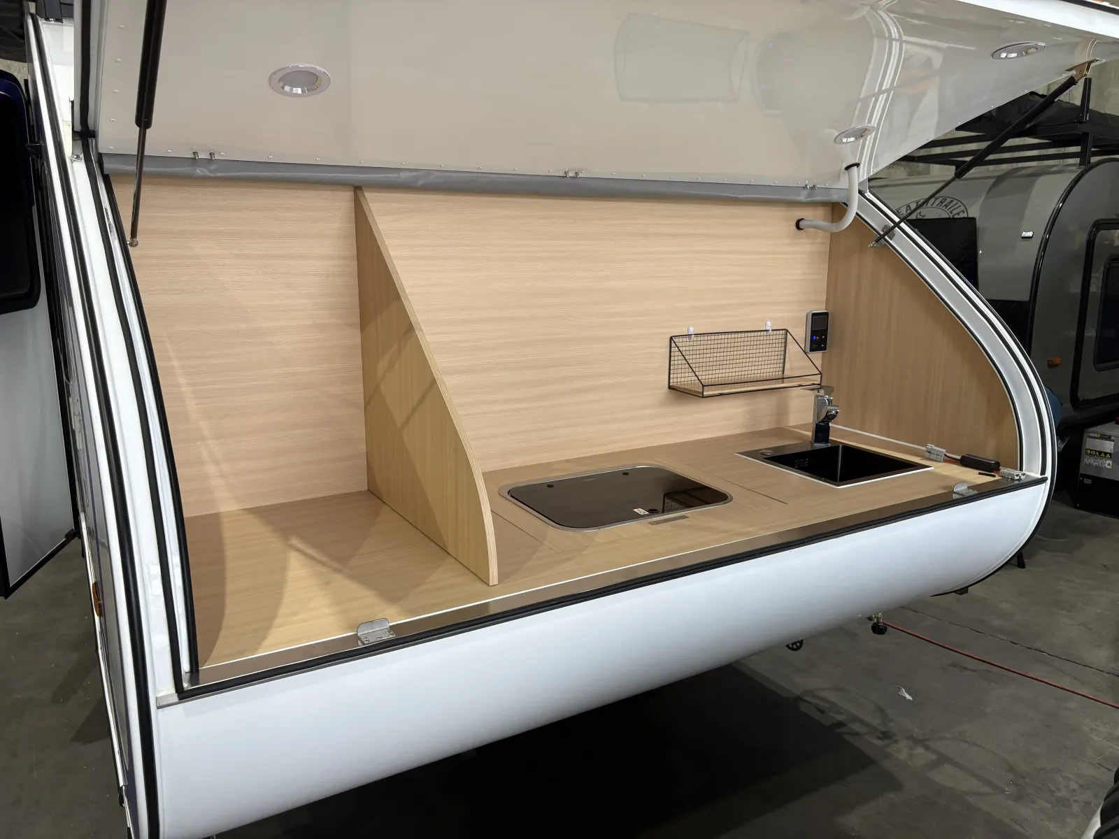 Breath Max rear galley with divider, glass-lidded cooktop, black sink, wire shelf and control panel