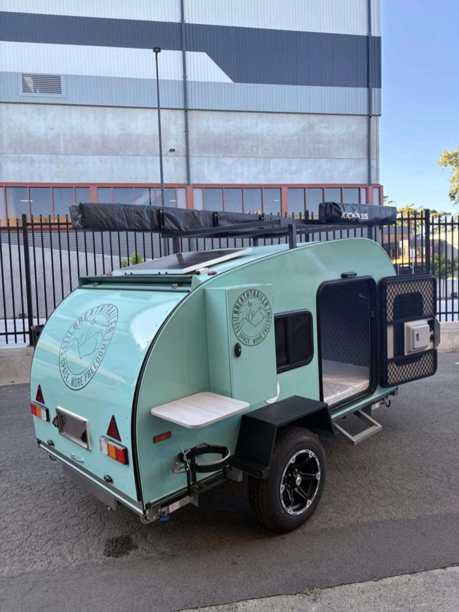 Breath Ultra in mint green with side door open, fold-out table, solar panel and roof awnings
