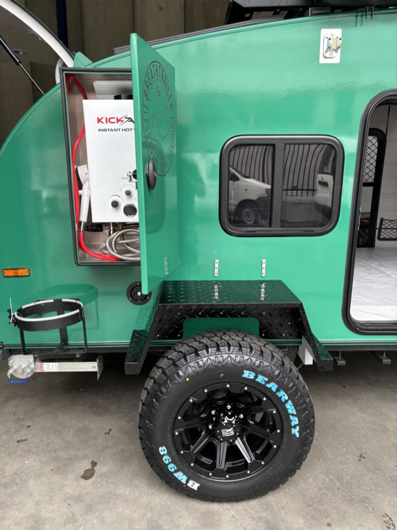 Breath Ultra all-terrain tyre and wheel under a chequer-plate guard, hot water compartment open above