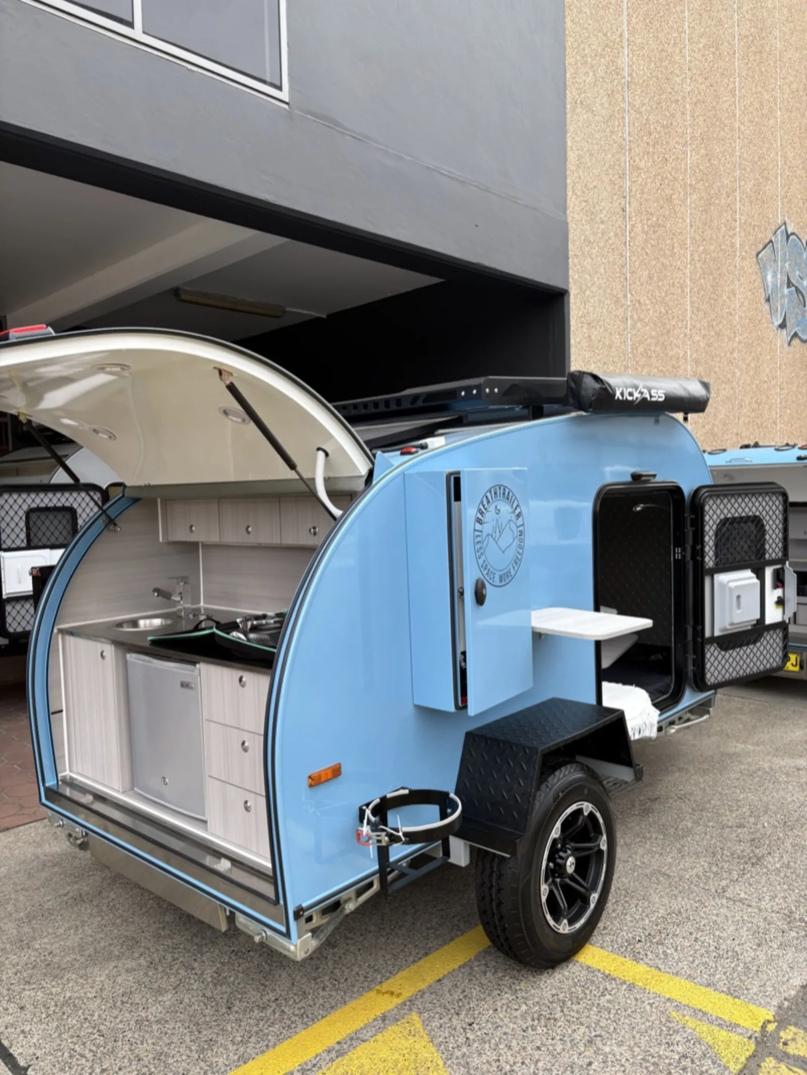 Breath Ultra in light blue with rear kitchen open showing sink, stove, fridge and drawers, side door open