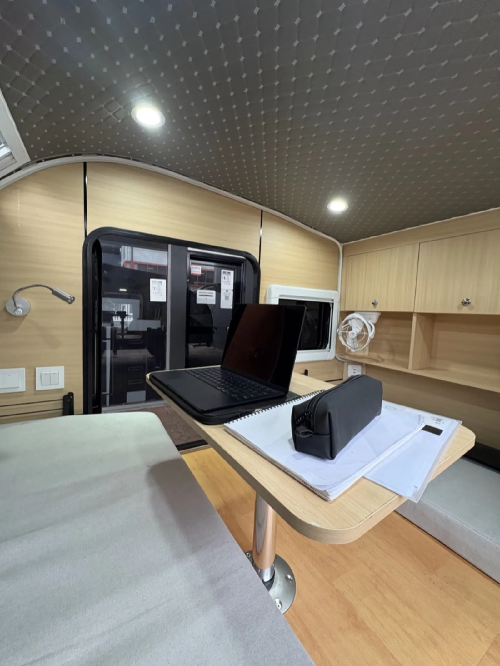 Breath Ultra interior with pedestal table holding a laptop and notebook, timber cabinets and reading light