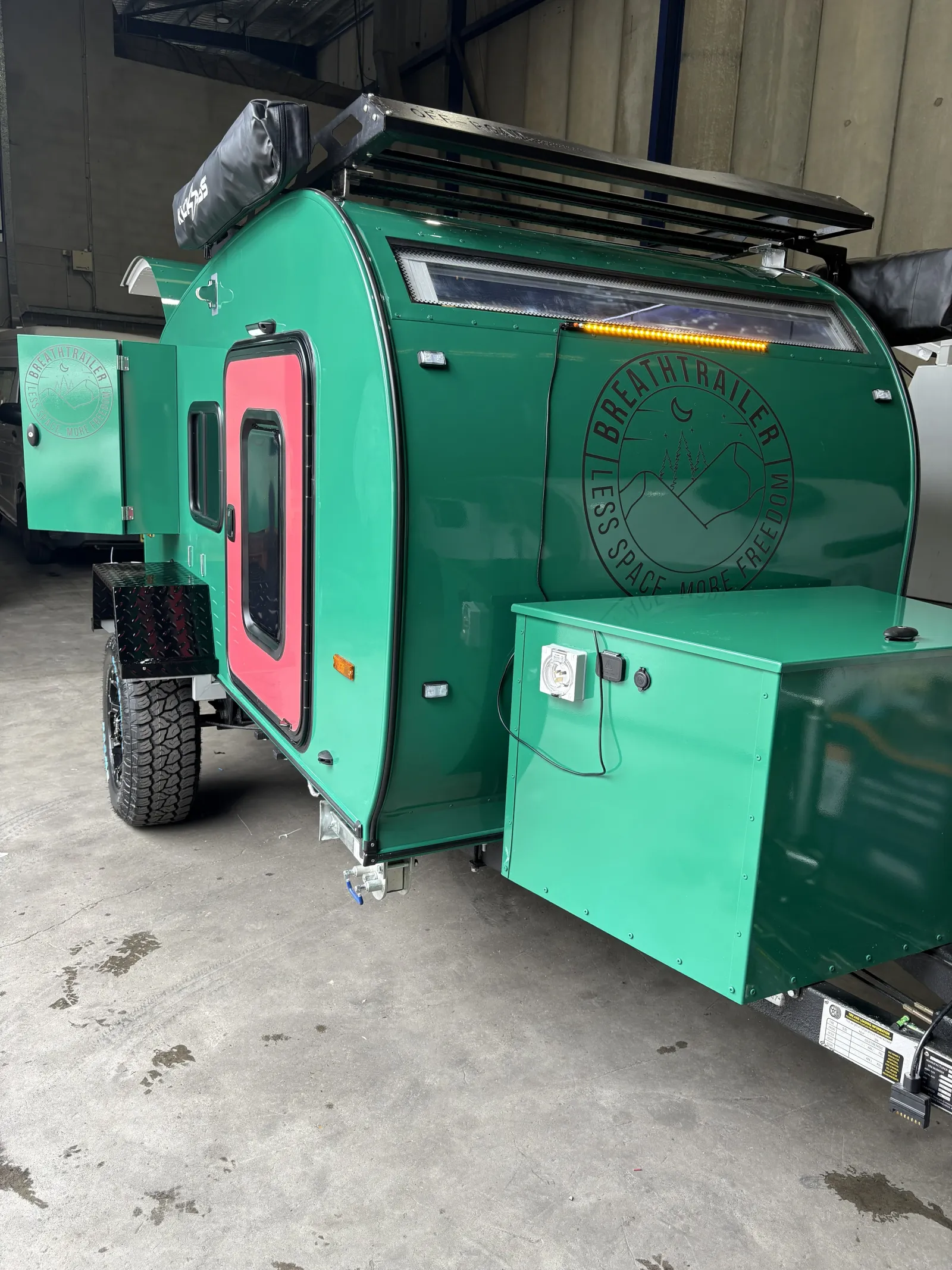 Breath Ultra in green from the front, showing toolbox, power inlet, roof rack and the compliance plate on the drawbar