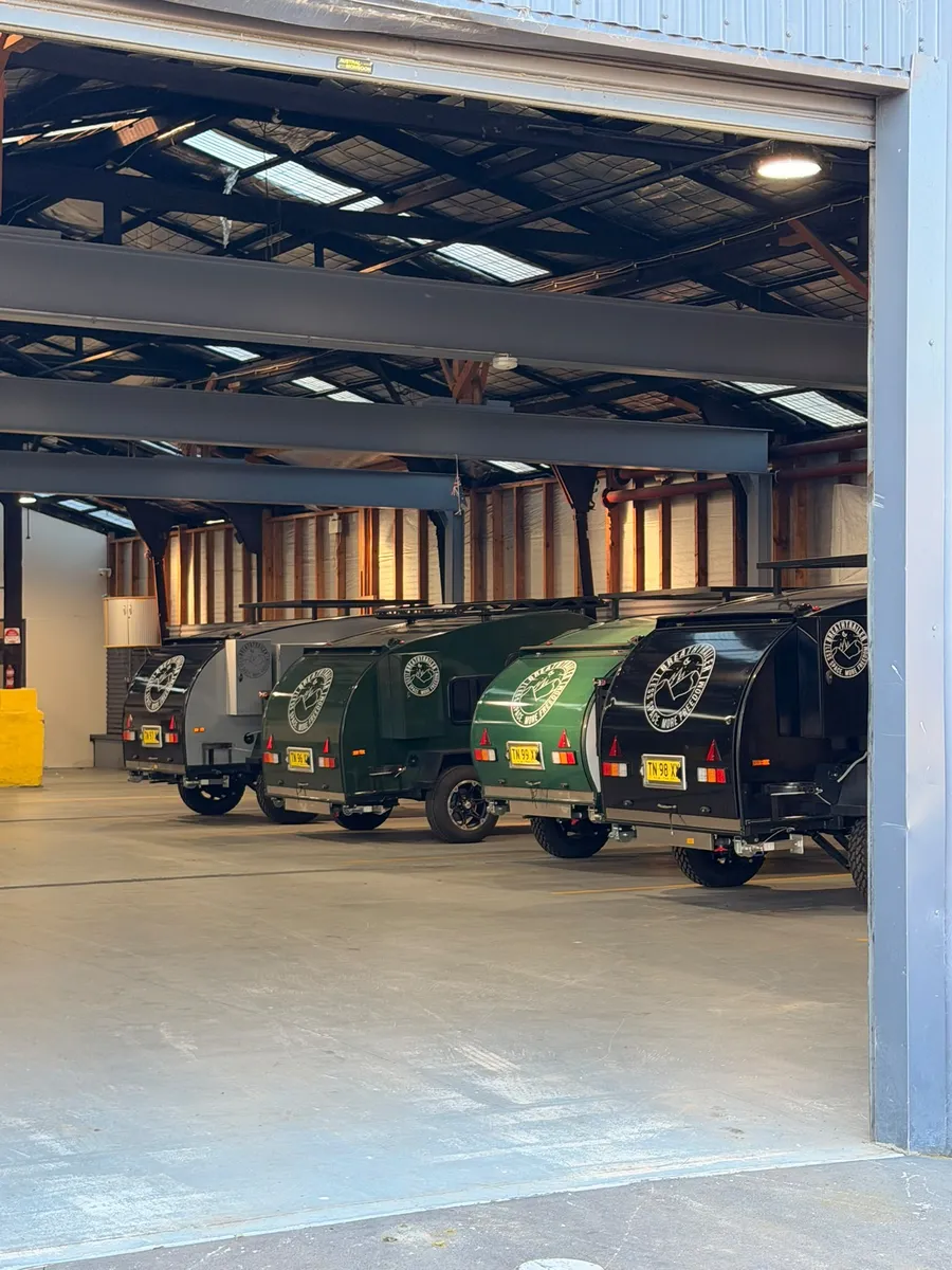 Row of green and black Breath teardrop campers parked inside the Breath Trailer Sydney warehouse