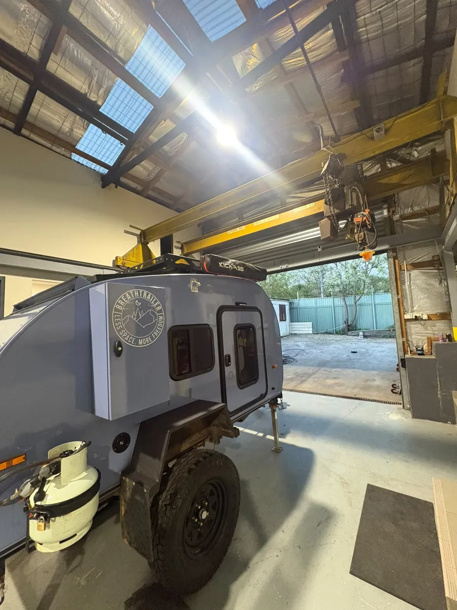 Blue Breath teardrop camper inside the Breath Trailer Sydney workshop under the overhead crane